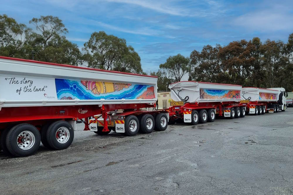 a long truck with three sections brightly painted 'the story of the land'